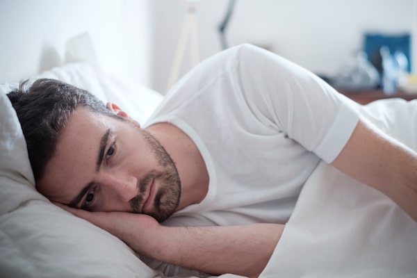 depressed man laying in bed